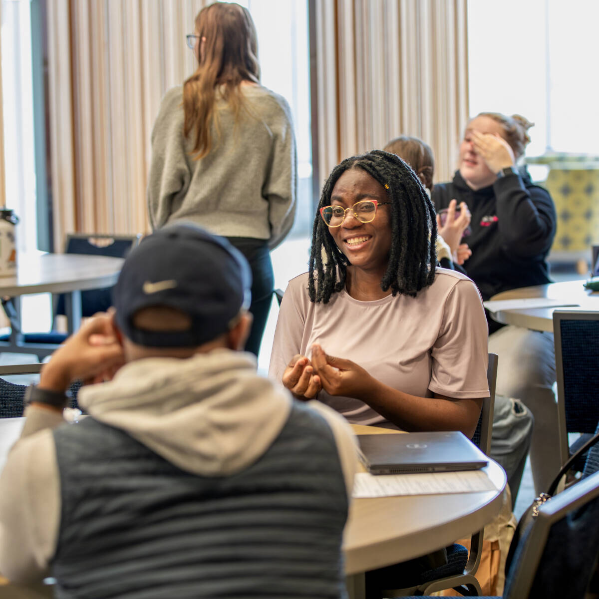 Students sitting at a round table, chatting and laughing
